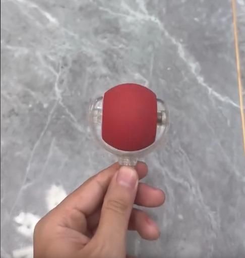 Hand holding a red and clear object against a marble background
