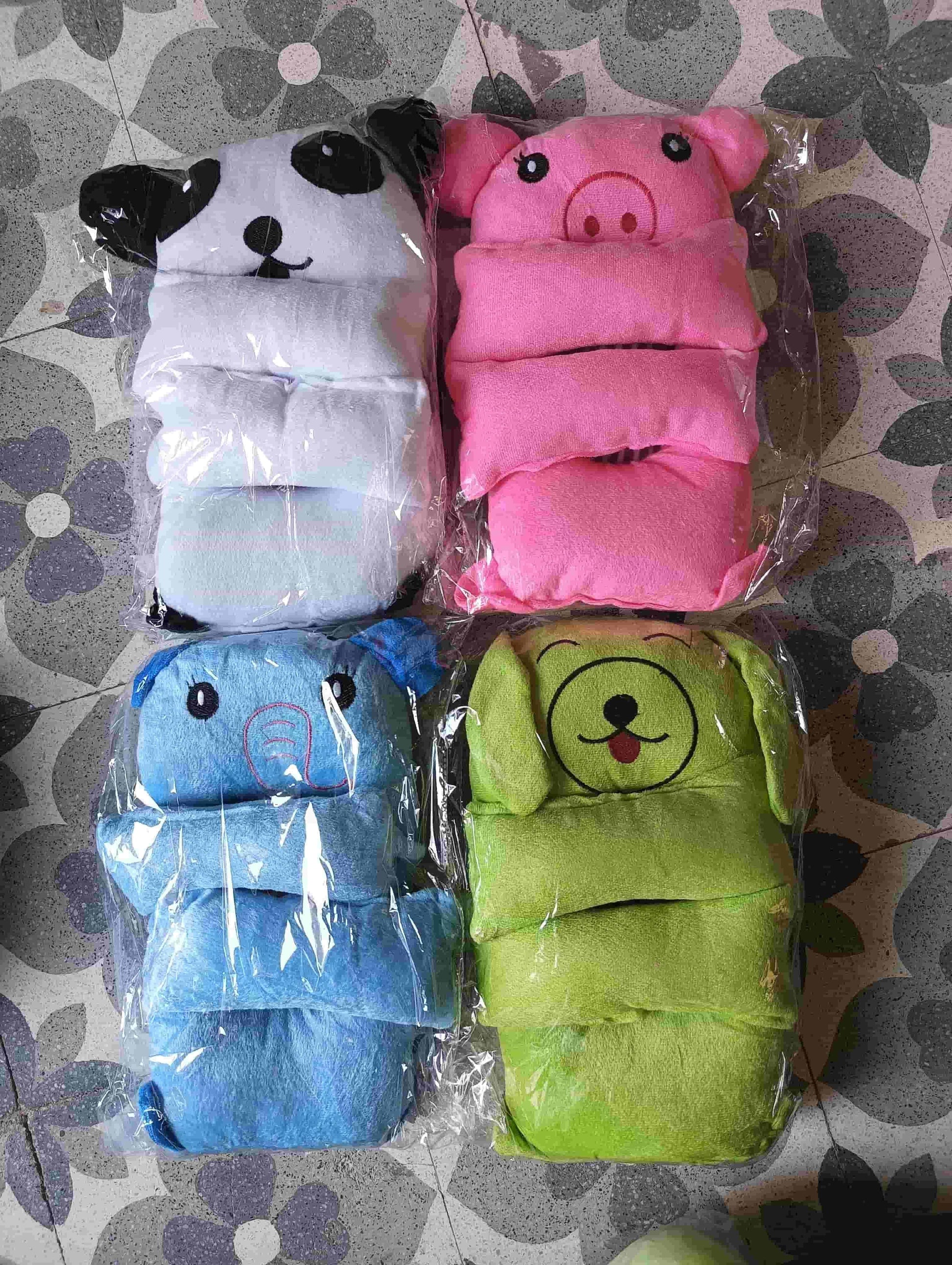 Four animal-themed baby diapers in plastic packaging on a patterned surface.